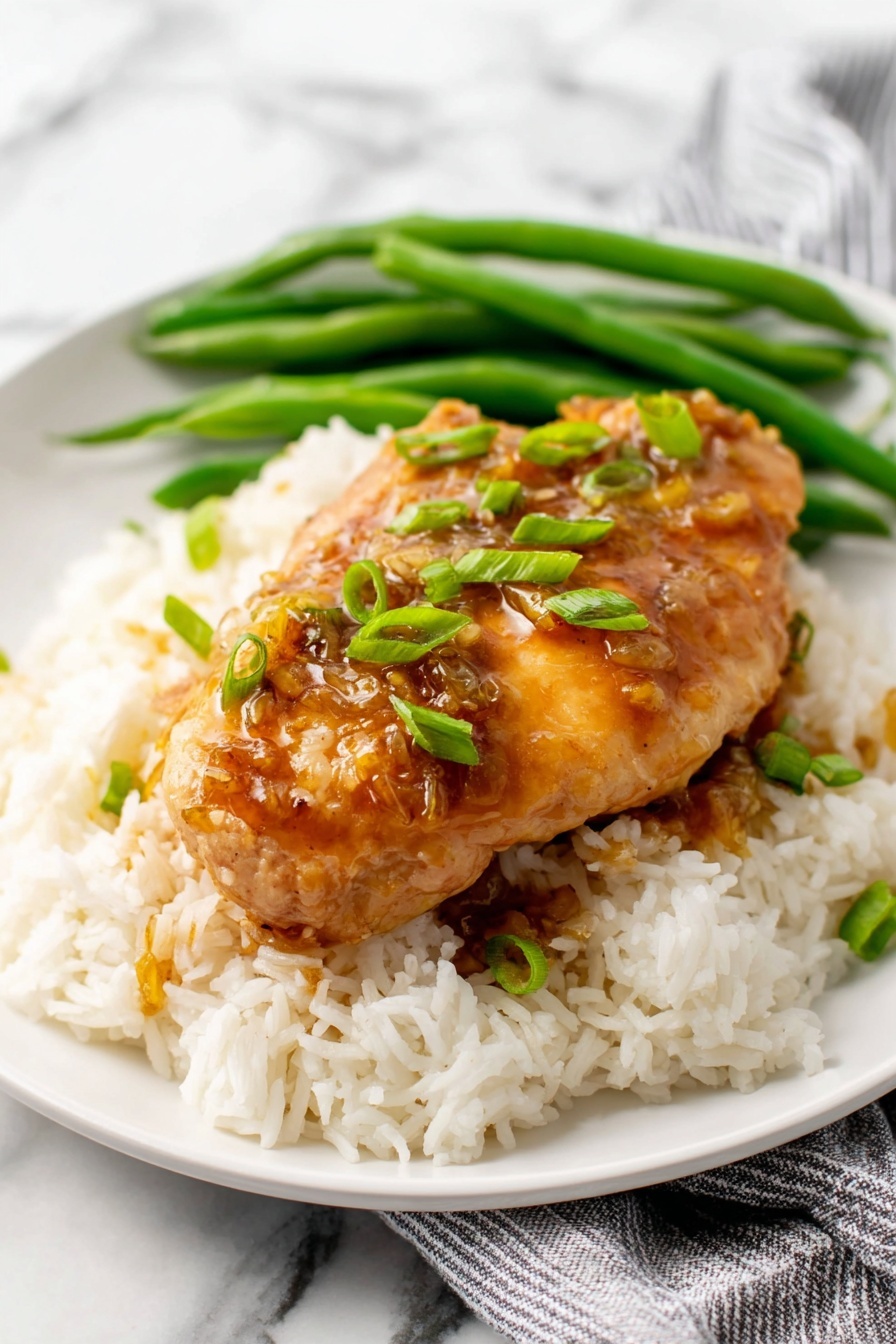 honey garlic chicken - The image shows several pieces of cooked chicken fillets placed in a dark pan, covered with a shiny brown sauce that looks sticky and thick. The chicken pieces are evenly coated with the sauce, giving them a glossy, richly colored appearance with small bits of green garnish scattered on top. The surface of the pan reflects light, making the sauce look wet and fresh. The close-up view highlights the texture of the chicken showing a slightly rough surface under the smooth sauce. The overall color palette is warm with hues of brown and hints of green from the garnish, all set against the pan’s dark background. Photo taken with an iphone --ar 2:3 --v 7