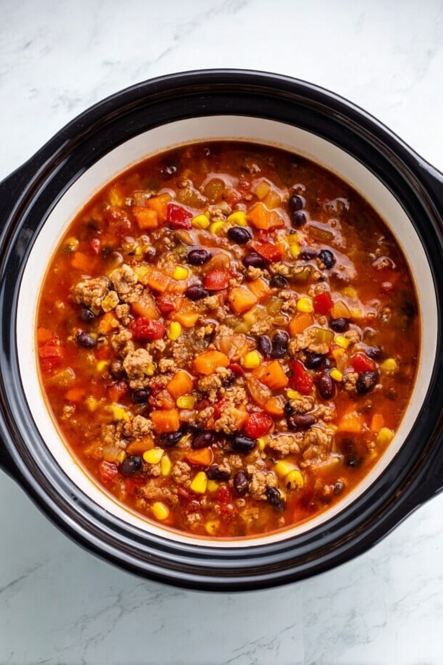 A white bowl filled with thick soup showing several layers of orange-red broth mixed with small chunks of light brown cooked meat, black beans, yellow corn kernels, and diced red and orange bell peppers, all floating evenly on the surface. The bowl sits on a white marbled surface, creating a clean and bright background. The soup’s texture looks hearty with small bits spread widely across the broth, giving it a colorful and dense appearance. Photo taken with an iphone --ar 2:3 --v 7