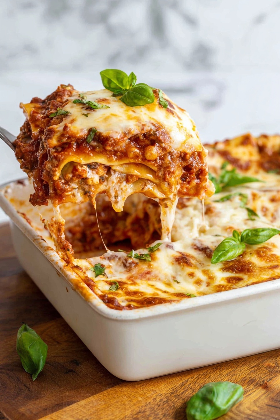 A square white baking dish filled with a thick, layered slice of lasagna being lifted by a utensil, showing several visible layers including a golden melted cheese top with browned spots, a rich red tomato sauce layer with chunks of meat and vegetables, creamy white cheese layers, and soft pasta sheets with a slightly rough texture. A few fresh green basil leaves are placed on top and around the dish. The dish sits on a wooden surface with a white marbled textured background. Photo taken with an iphone --ar 2:3 --v 7