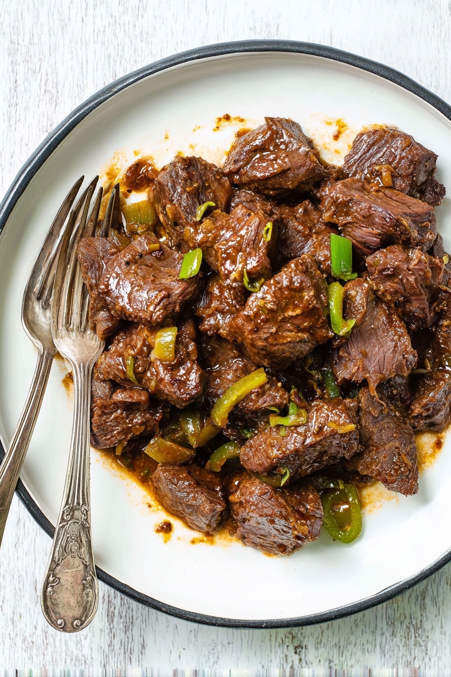 Chunks of cooked beef in a thick, dark brown sauce with visible bits of cooked green peppers and onions, all spread over a round white plate with a thin black rim. Two vintage silver forks rest on the left side of the plate, partially touching the meat. The plate sits on a white marbled surface. The beef looks tender with a slightly shiny texture from the sauce. photo taken with an iphone --ar 2:3 --v 7
