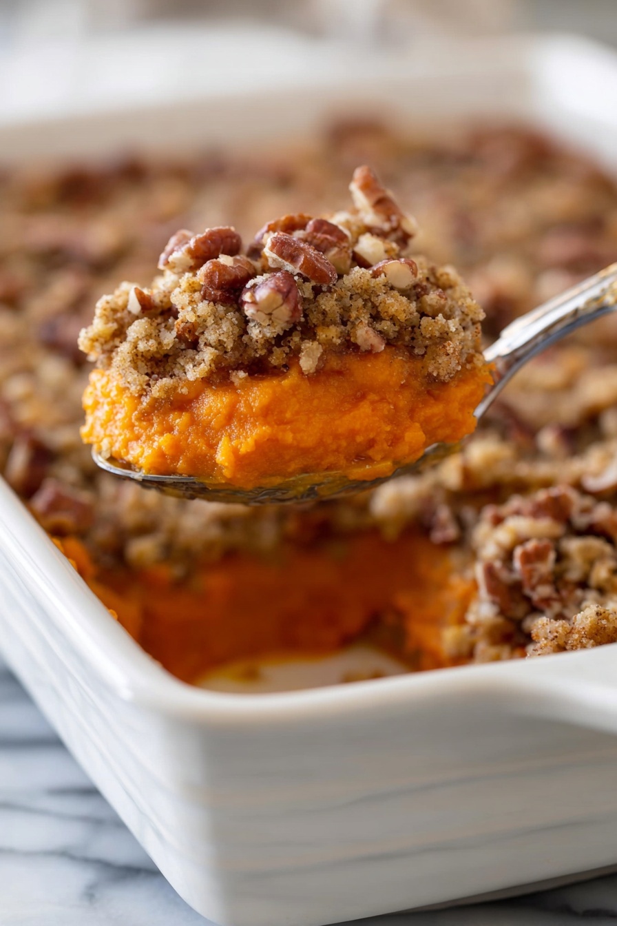 A close-up shows a white rectangular baking dish filled with a layered sweet potato casserole. The bottom layer is smooth and bright orange, soft in texture. On top is a thick crumb topping with chopped pecans, light brown and slightly rough, adding a crunchy texture. The spoon lifting a portion reveals both layers clearly, with the contrast between the soft orange and the crumbly pecan topping. The dish sits on a white marbled surface. photo taken with an iphone --ar 2:3 --v 7