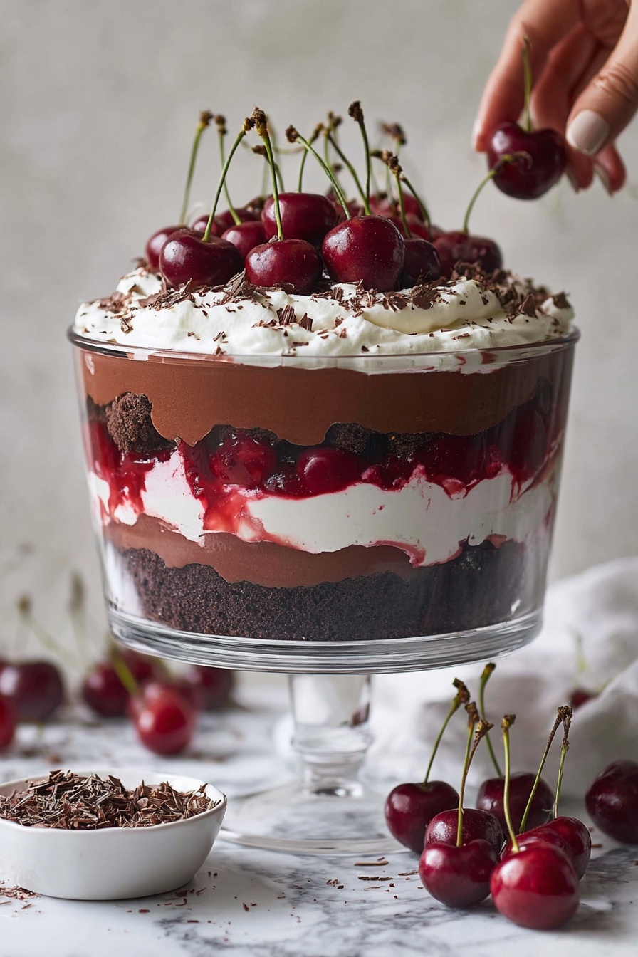 The dessert is in a clear glass bowl on a glass stand, showing six visible layers. Starting from the bottom, the first layer is dark, crumbly chocolate cake. Above it is a smooth chocolate pudding layer that gently wraps around the cake pieces. The third layer is bright red cherry sauce, thin but rich in color. The fourth layer is fluffy white cream, slightly uneven and soft. Next, another thick layer of chocolate pudding, darker and shiny, with some dark cake crumbs mixed in. On top is a thick, whipped cream layer with a few chocolate shavings scattered around, crowned by a bunch of whole bright red cherries with green stems standing upright. The scene is set on a white marbled surface with fresh cherries and a small white bowl of chocolate shavings nearby. Photo taken with an iphone --ar 2:3 --v 7