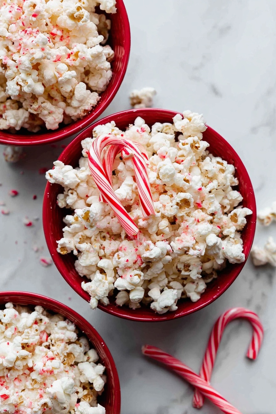 There are three red bowls filled with white popcorn with red sprinkles on top, placed on a white marbled surface. Two candy canes with red and white stripes are placed on top of the popcorn in the center bowl, and one candy cane lies on the surface near the bottom right bowl. The popcorn looks fluffy with small bits of red sprinkled throughout. The light is bright and soft, highlighting the textures of the popcorn and candy canes. photo taken with an iphone --ar 2:3 --v 7