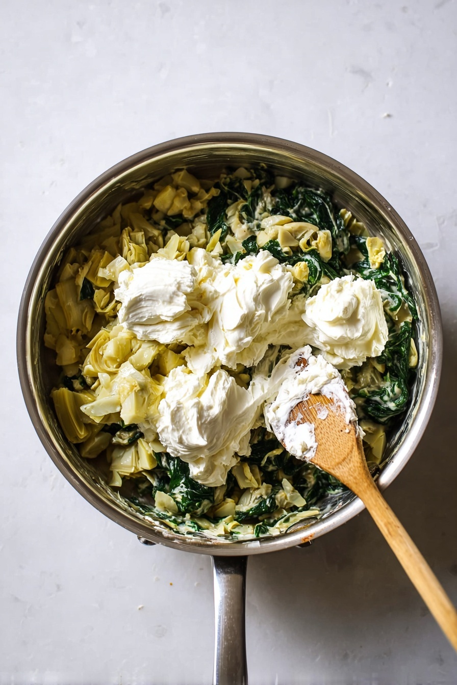 A bowl filled with creamy baked pasta showing two clear layers: the bottom layer consists of rigatoni pasta mixed with spinach and white sauce, creating a smooth, pale cream texture with dark green spinach bits scattered throughout; the top layer features a golden-brown crust with melted cheese slightly browned in spots, giving a crispy, bubbly appearance with some pasta edges darker and crispy; a silver fork is placed inside the bowl on the left side, resting against the food; the bowl is white and sits on a white marbled surface, with a small dish containing salt and pepper visible in the top right corner. photo taken with an iphone --ar 2:3 --v 7
