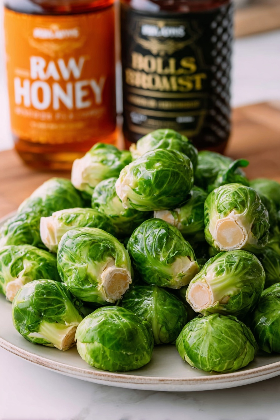 The image shows a close-up of a grilled Brussels sprout held by a silver fork. The Brussels sprout is golden brown and slightly charred with visible layers of softened green leaves and a glossy, glazed surface. The background contains more Brussels sprouts with similar browning and hints of green leaves spread around on a white plate. The setting is on a white marbled surface. photo taken with an iphone --ar 2:3 --v 7
